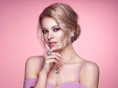珠宝广告用珠宝描绘美丽的金发女人模特女孩用珍珠指甲修剪指甲优雅的发型宝石银美容时尚配饰完美的化妆粉红色的背景背景