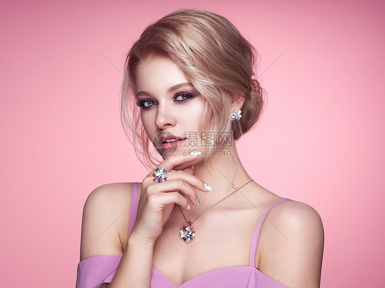 用珠宝描绘美丽的金发女人模特女孩用珍珠指甲修剪指甲优雅的发型宝石银美容时尚配饰完美的化妆粉红色的背景图片