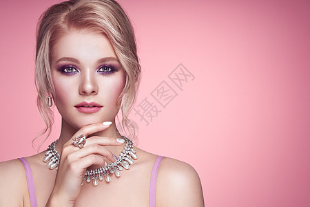 用珠宝描绘美丽的金发女人模特女孩用珍珠指甲修剪指甲优雅的发型宝石银美容时尚配饰完美的化妆粉红色的背景图片