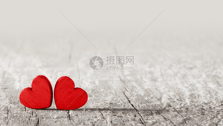 两颗红色的手工心旧的开裂的木制背景上,有文字的两颗红心老木头上图片