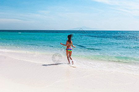美丽的快乐女孩举起手臂跑到热带海洋快乐的女孩奔向大海图片