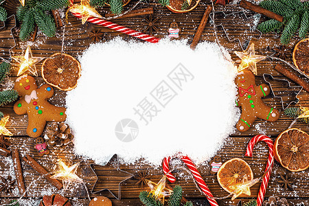 圣诞食品框架姜饼饼干,香料装饰木制背景与白色雪上圣诞食品框架图片
