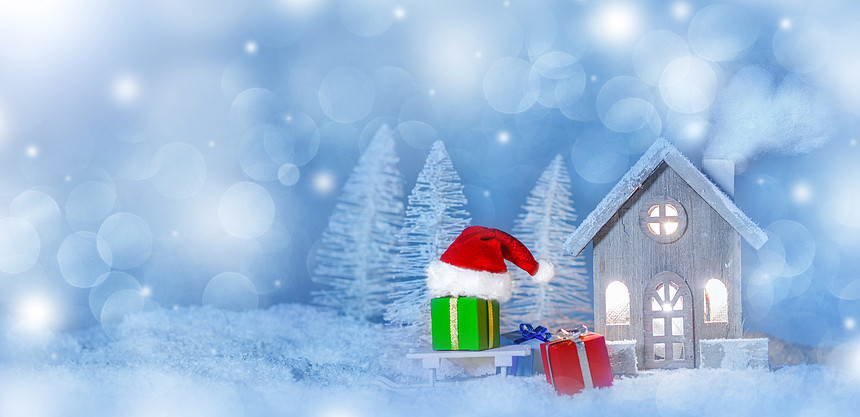 圣诞卡与小发光装饰房子,礼物圣诞老人帽雪橇上的雪上的童话冬天冷杉森林背景下雪新年明信片文本房子圣图片