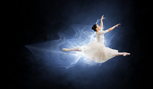 优雅的女舞者穿着白色的连衣裙,黑暗的背景下跳芭蕾的舞者图片