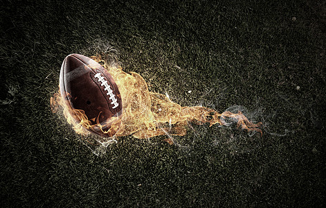 橄榄球黑暗背景下的火焰中美国足球比赛的图片