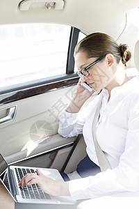 女高管汽车上用笔记本电脑时用手机交谈图片