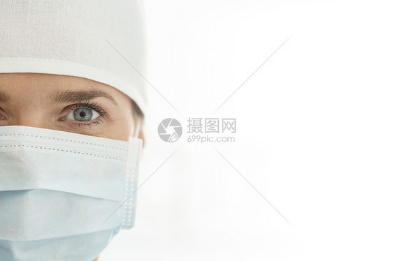 女医生戴着外科口罩帽子白色背景下的特写肖像图片
