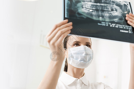 牙科诊所检查X光时,女牙医戴着口罩图片