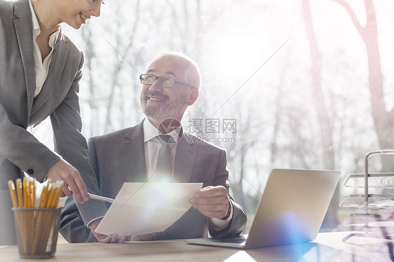 商界人士有个队会议波兰华沙,中段女商人与位微笑的高级商人办公桌前着办公室的窗户讨论文件图片