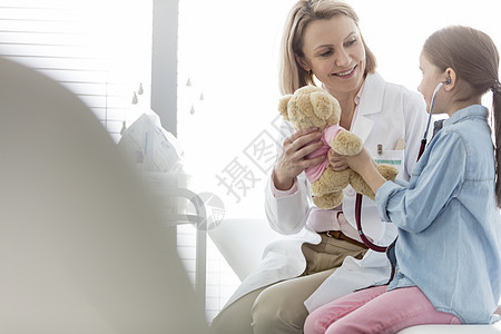 微笑的医生把泰迪熊给医院的女孩图片
