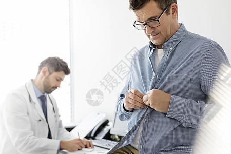 病人脱衣服检查,而医生医院阅读医疗报告图片