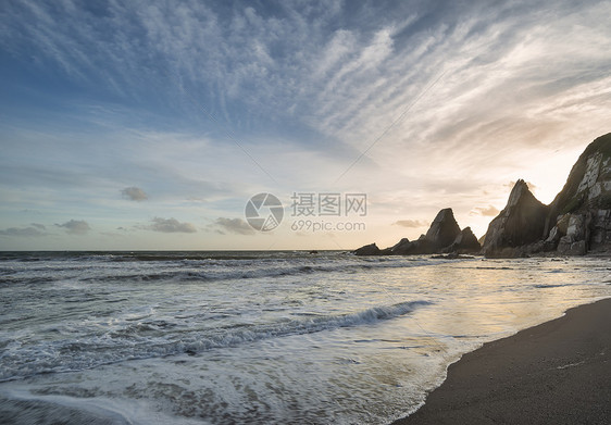 美丽的日落景观图像韦斯特康贝海滩德文英格兰与锯齿状的岩石海滩惊人的云图片