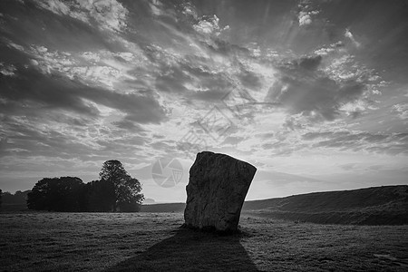 美丽的黑白夏季日出景观的新石器时代站立的石头英国农村与华丽的光与背景雾图片