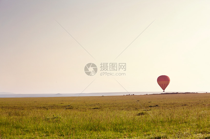 日出马赛马拉,灌木丛上方有个气球旅行背景图片