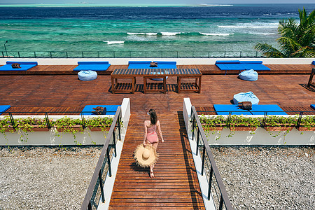 穿着红色条纹单件泳衣的女人热带海滩露台甲板上散步马尔代夫的暑假背景图片