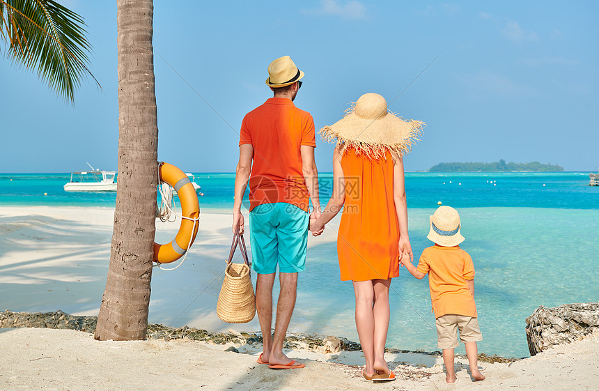 家人海滩上,穿着橙色衣服的轻夫妇三岁的男孩棕榈树下马尔代夫的暑假图片