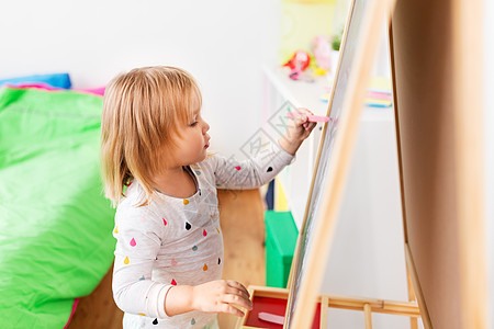 童,休闲人的快乐的小女孩家里画粉笔板快乐的小女孩家里画粉笔板图片