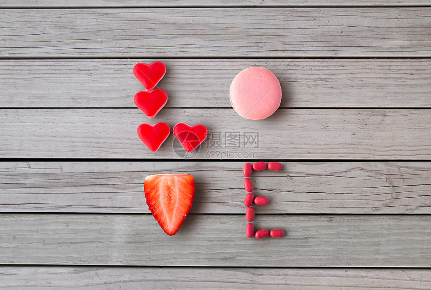 情人节,糖果糖果的文字爱由红色心形糖果,粉红色通心粉饼干草莓灰色木板背景用糖果的爱图片