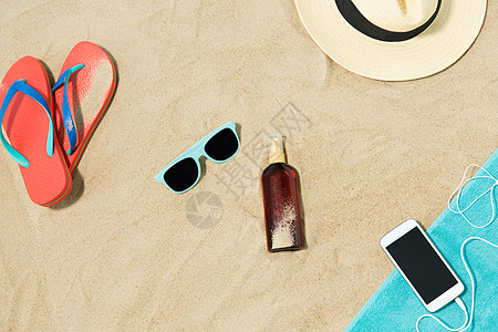 假期暑假智能手机与耳机毛巾,草帽,太阳镜,拖鞋瓶防晒油海滩沙子海滩上的智能手机帽子拖鞋窗帘图片
