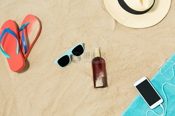 假期暑假智能手机与耳机毛巾,草帽,太阳镜,拖鞋瓶防晒油海滩沙子海滩上的智能手机帽子拖鞋窗帘图片