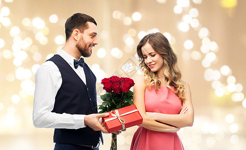 情人节,夫妇,关系人的快乐的男人给女人花,并呈现米色背景节日灯快乐的男人给女人鲜花礼物图片