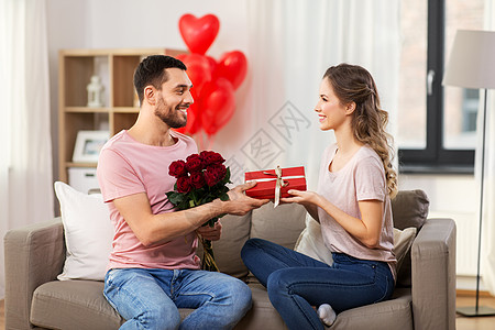 情人节,夫妻,人际关系人的快乐的男人给女人鲜花礼物家里快乐的男人给女人鲜花,并家里礼物背景图片