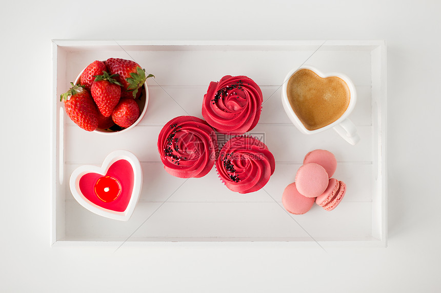 情人节糖果纸杯蛋糕与红色奶油霜,马卡龙,心形咖啡杯,蜡烛草莓托盘情人节的红色糖果图片