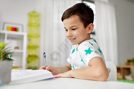 教育,童人的快乐的学生男孩与书籍写作笔记本家里学生男孩家里把书写笔记本上图片