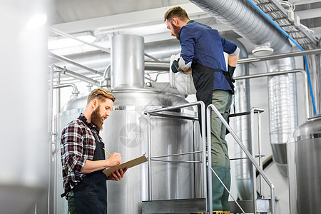 制造,商业人的男人与剪贴板麦芽工作啤酒厂啤酒厂水壶啤酒厂水壶啤酒厂剪贴板的男人背景图片