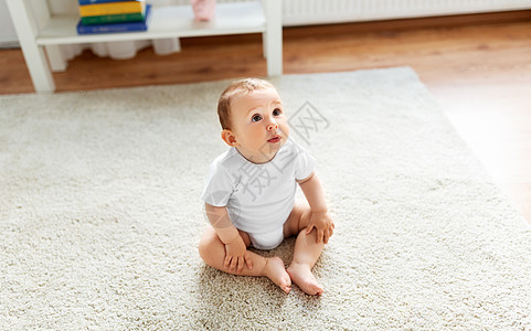 小婴儿坐家里的地板上仰望图片