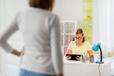 教育,技术学校学生女孩与平板电脑分散家庭作业母亲进入儿童室学生女孩家庭作业期间用平板电脑图片