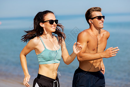 健身,运动技术快乐的夫妇与耳机运行夏季海滩夫妇带着耳机海滩上跑来跑图片