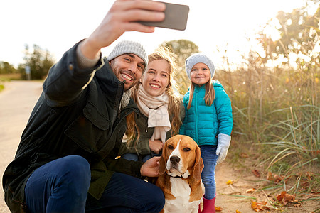 家庭,宠物人的快乐的母亲,父亲小女儿与比格犬自拍智能手机户外秋天秋天狗自拍的幸福家庭图片