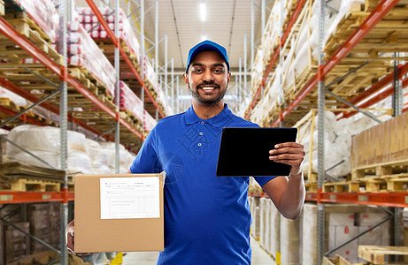邮件服务,技术装运快乐的印度送货人员仓库工人与包裹盒平板电脑蓝色制服货物背景送货人员与平板电脑盒子仓库图片