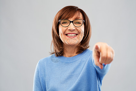 微笑的老年女子指着镜头图片