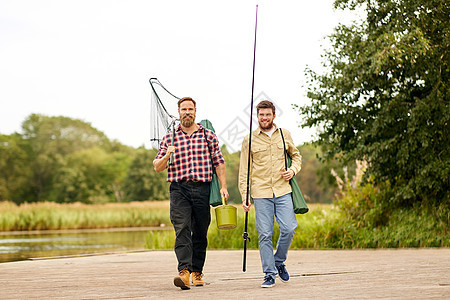 休闲人们的快乐的朋友与钓竿舀网沿着木墩湖泊河流湖边河边鱼竿网的朋友图片