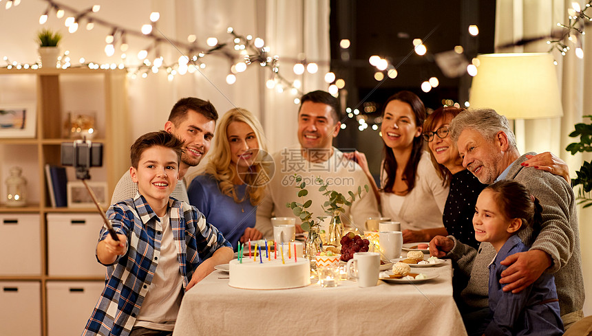 庆祝,假日人们的幸福的家庭家里举行生日茶会,并自拍杆上用智能手机拍照家庭生日派自拍图片