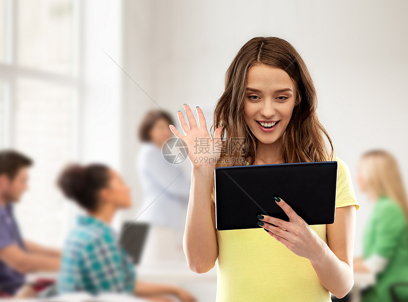 高中,教育技术快乐的十几岁的学生女孩穿着黄色T恤,平板电脑上视频通话,并挥手移交教室教师背景学生女孩学校的平图片