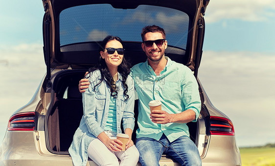 旅行,暑假,公路旅行,休闲人们的快乐的夫妇喝咖啡次杯子坐后备箱的掀背车户外幸福的情侣掀背车后备箱里喝咖啡图片