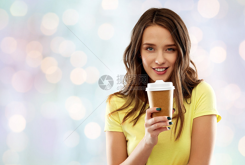 外卖人们的轻的女人十几岁的女孩穿着T恤,节日的灯光背景下喝咖啡轻女子十几岁的女孩喝咖啡图片