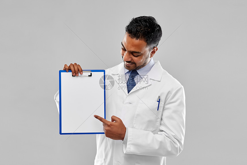 医学,科学职业微笑的印度男医生科学家穿着白色外套,灰色背景的剪贴板上空白纸剪贴板上白纸的医生科学家图片