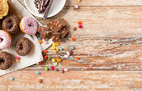 垃圾食品,糖果健康的饮食釉甜甜圈,巧克力,滴糖果块蛋糕木桌上桌子上同的糖果图片