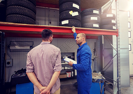 汽车服务,维修,维护人的机械师与剪贴板轮胎给人汽车商店汽车机械师带轮胎的人汽车商店图片