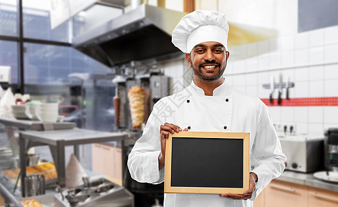 烹饪,职业人的快乐的印度男厨师托克与空白黑板菜单上的烤肉店厨房背景快乐的印度厨师烤肉店用黑板图片
