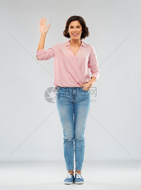 时尚,风格人的快乐的微笑轻女人穿着条纹衬衫,牛仔裤运动鞋灰色背景上挥手穿着衬衫牛仔裤的轻女人挥舞着手图片