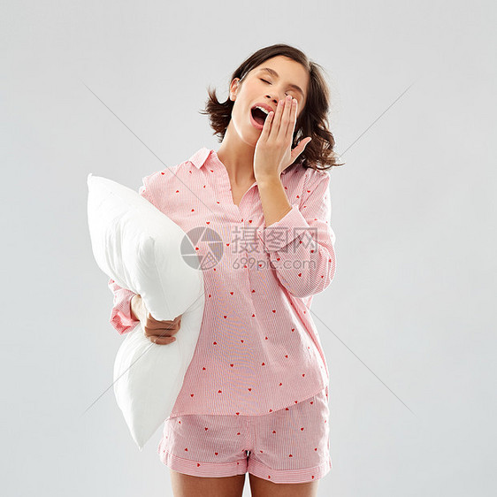 人们睡觉时间的快乐的困倦哈欠轻妇女睡衣抱着枕头灰色的背景睡眼惺忪的轻女人睡衣枕头图片