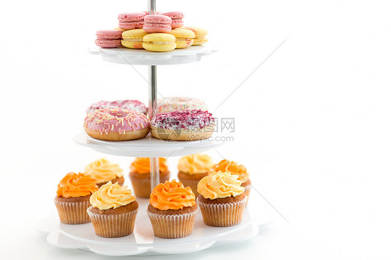 快餐糖果釉甜甜圈,纸杯蛋糕马卡龙白色背景上站立看台上的琉璃甜甜圈,纸杯蛋糕马卡龙图片