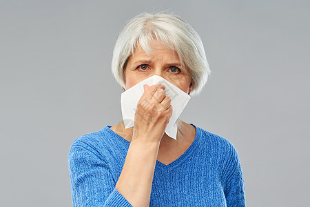健康护理,流感卫生生病的老妇女灰色背景下鼻子纸巾上生病的老年女子鼻子纸巾上图片