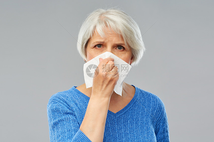 健康护理,流感卫生生病的老妇女灰色背景下鼻子纸巾上生病的老年女子鼻子纸巾上图片