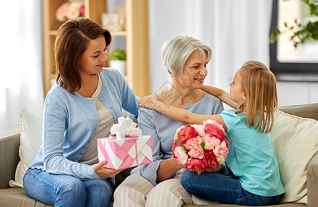 家庭,代生日快乐的母亲带着礼品盒女儿拥抱祖母家孙女拥抱问候祖母图片
